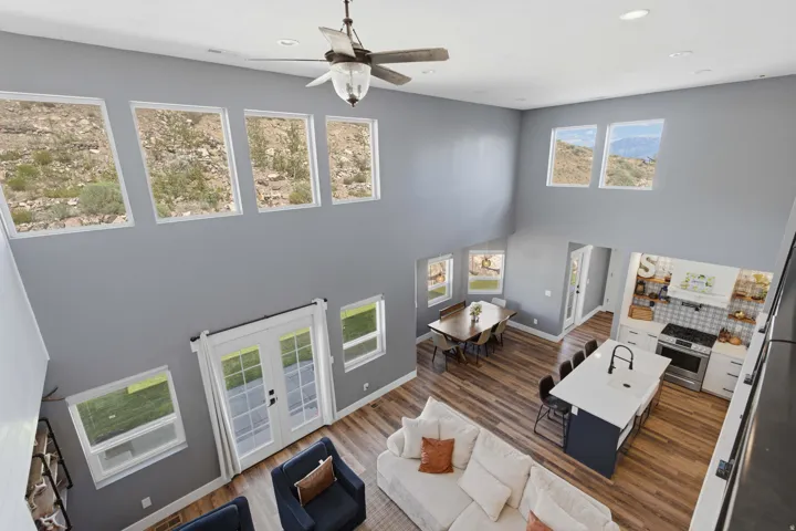 High ceilings with upper transom windows, French doors, wood-finish flooring, white shaker cabinetry, and an extended island