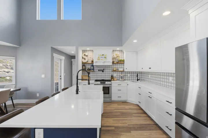 Spacious kitchen featuring white cabinetry, a large center island with a sink, stainless steel appliances, and wood-finish flooring