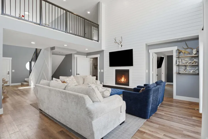 18 ft,Vaulted ceiling, wood-finish flooring, two-story fireplace with shiplap surround, recessed lighting, and a metal railing balcony