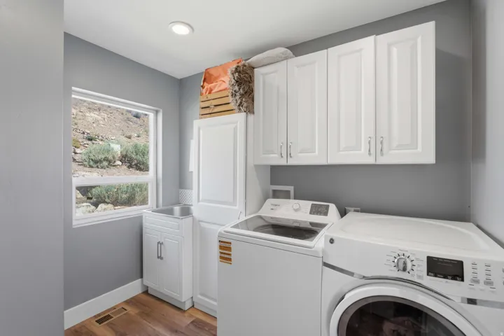 Laundry area with white cabinetry, wood-finish flooring, a utility sink, and recessed lighting