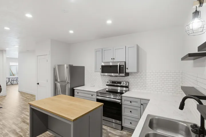 Kitchen featuring stainless steel appliances, white subway tile backsplash, light gray cabinetry, and wood-finish flooring