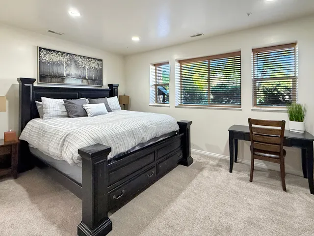 Spacious primary suite with king bed, desk space, beautiful furniture, mounted smart TV, and ensuite bath with double vanities.