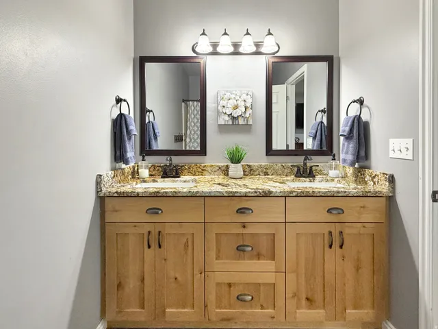 Spacious ensuite primary bath with double vanity, gorgeous granite countertops, and knotty alder cabinets.