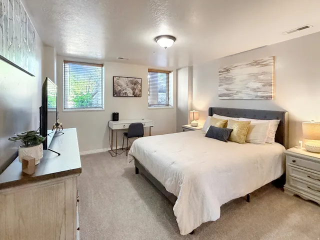 Bedroom 2 located in the basement with beautiful furnishings, queen bed, large smart TV, and desk space for working.