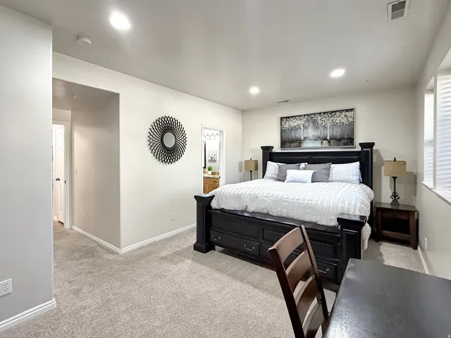 Spacious primary suite with king bed, desk space, beautiful furniture, mounted smart TV, and ensuite bath with double vanities.