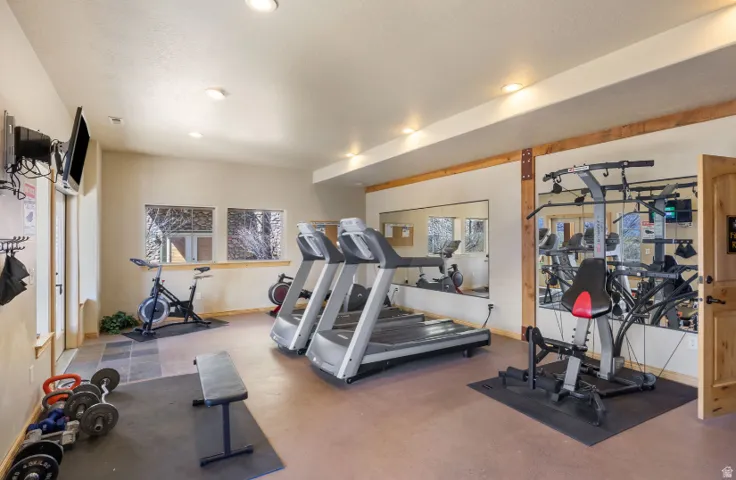 Dedicated fitness room featuring recessed lighting, a wood-finish door, and integrated wall mirrors