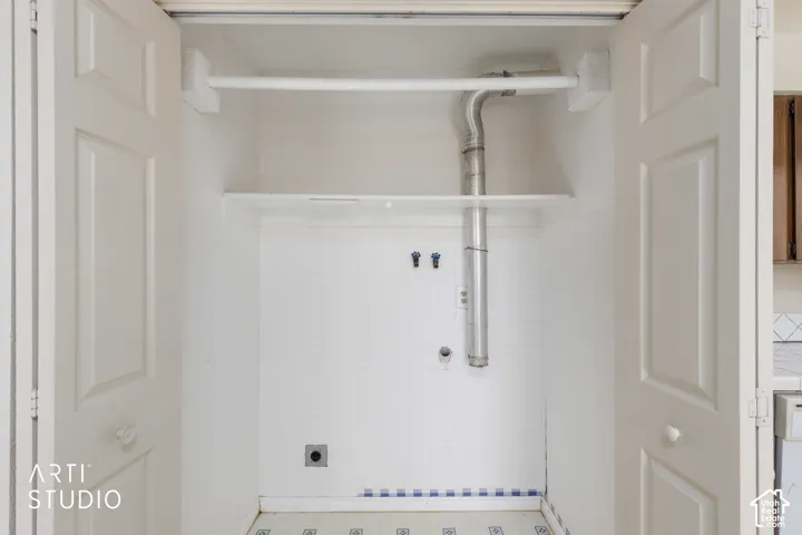 Built-in laundry closet with bifold doors, utility hookups, and integrated shelving