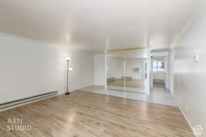 Wood-finish flooring, mirrored sliding doors, crown molding, and tiled entry