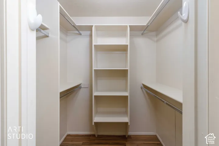 Walk-in closet featuring built-in shelving, multiple hanging rods, and wood-finish flooring