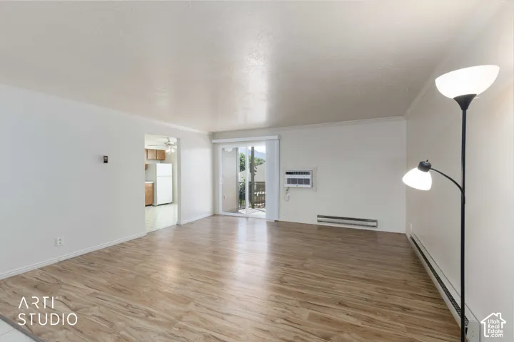 Wood-finish flooring, white painted walls, sliding glass door, and a wall-mounted air conditioning unit