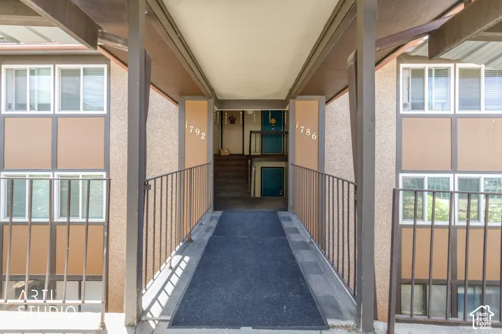 Covered entryway featuring a textured facade and brown railing
