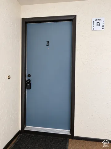 Blue-painted entry door featuring a dark metal frame, polished hardware, and a door-mounted viewer