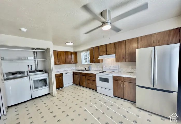 Kitchen featuring wood cabinetry, white appliances, and a stainless steel refrigerator