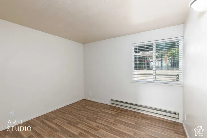 Wood-finish flooring, white walls, and a window with blinds