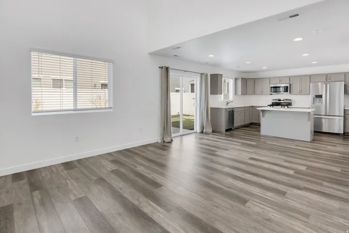 Vaulted ceiling, wood-finish flooring, sliding glass door, recessed lighting, and stainless steel appliances