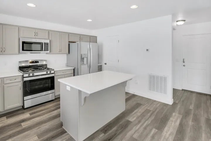 Kitchen featuring stainless steel appliances, light gray cabinetry, white countertops, and wood-finish flooring