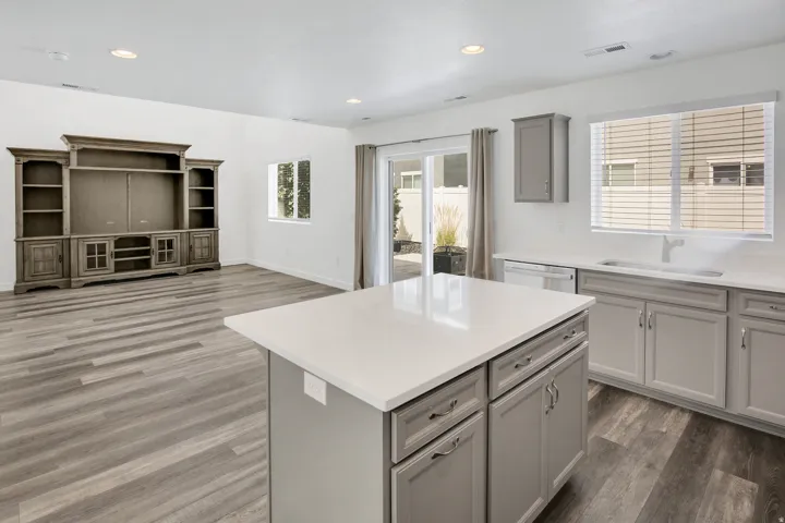 Open concept living space featuring wood-finish flooring, recessed lighting, a kitchen island with stone countertop, and light gray cabinetry