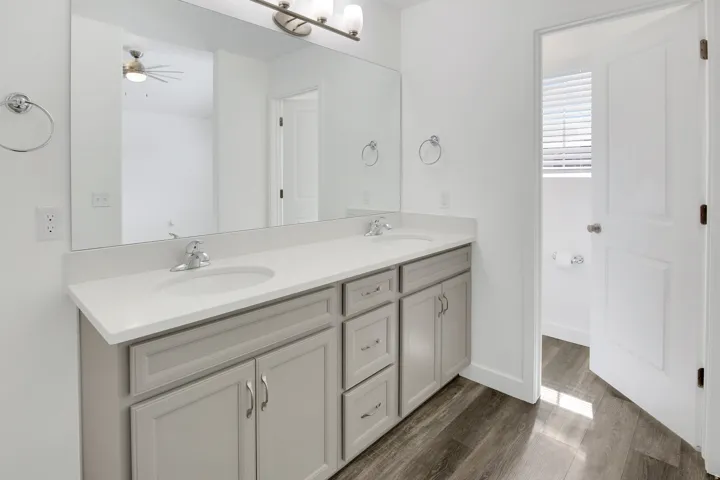 Spacious dual-sink vanity with wood-finish cabinetry, white quartz countertop, and polished chrome fixtures