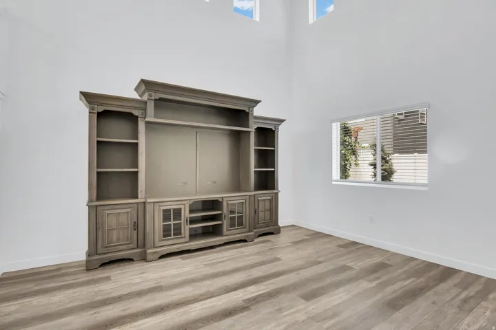 Open-concept room featuring high ceilings, wood-finish flooring, and crisp white walls