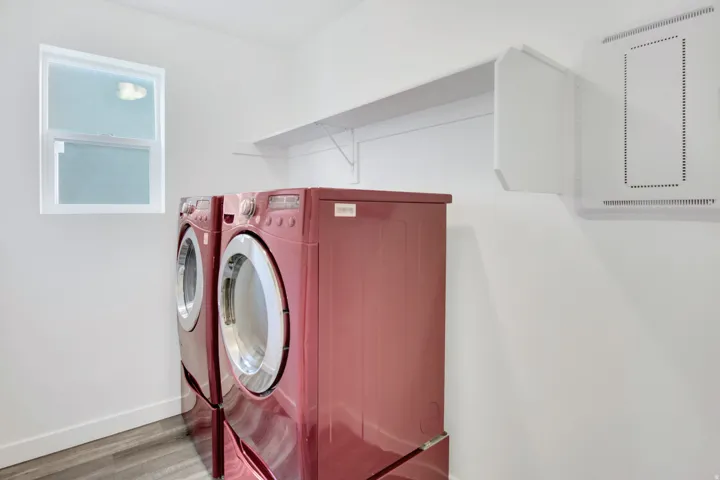 White shelving unit, wall-mounted utility panel, and wood-finish flooring