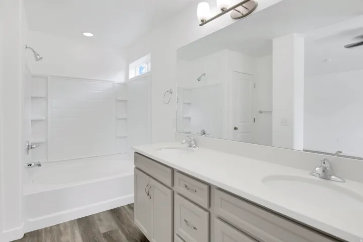 Dual vanity with light gray cabinetry, white countertops, and chrome fixtures