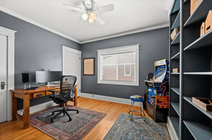Hardwood flooring, painted walls, built-in shelving, white trim, and a ceiling fan with integrated lighting