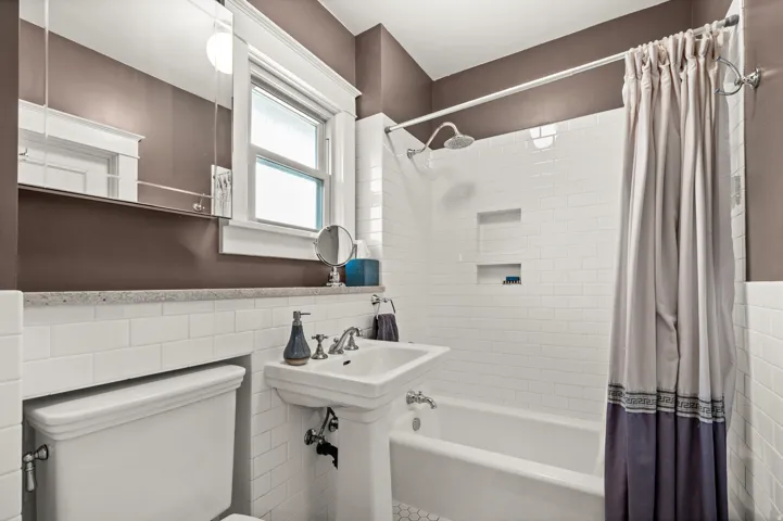 White subway tile walls with a built-in shower niche and a pedestal sink