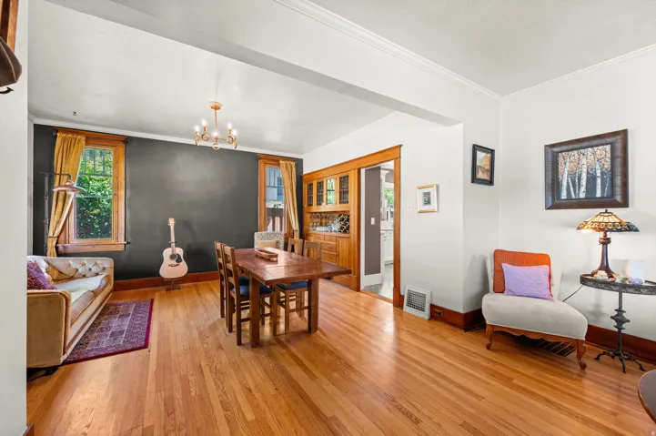 Hardwood flooring throughout, a brass chandelier, and built-in wood cabinetry with glass fronts