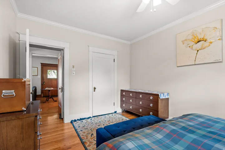 Hardwood flooring, crown molding, white trim, and a ceiling fan