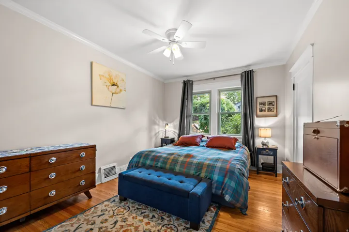 Hardwood flooring, crown molding, white trim, dual windows, and a ceiling fan