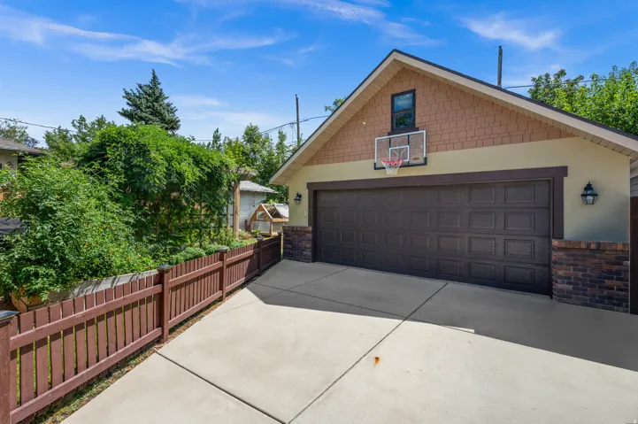 Two-car garage with a paneled door, concrete driveway, and exterior lighting