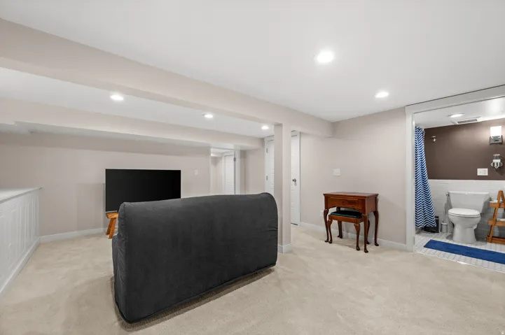 Recessed lighting throughout, wall-to-wall carpeting, built-in white cabinetry, full bathroom with white subway tile, and wall-mounted light fixtures