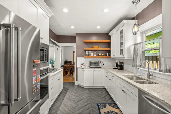 Kitchen featuring white cabinetry, stainless steel appliances, herringbone-patterned flooring, light-toned countertops, and recessed lighting