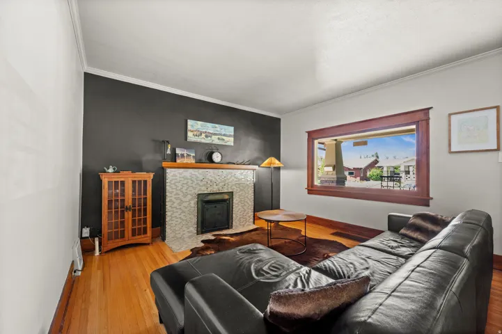 Hardwood flooring, tiled fireplace surround, fireplace insert, and wood window trim