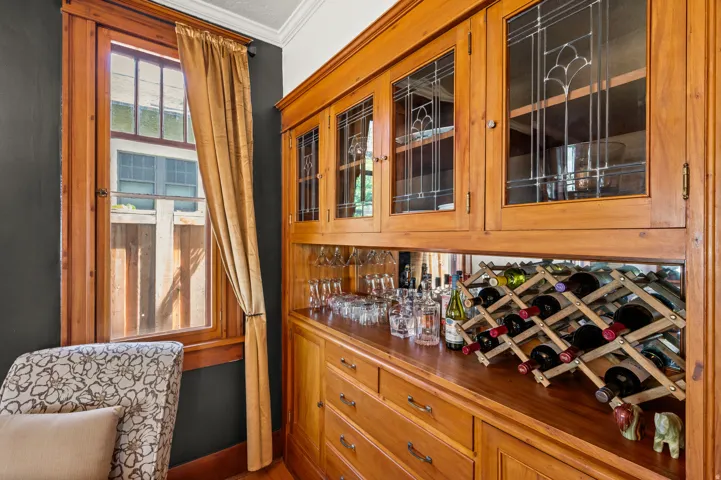 Built-in wood cabinetry with leaded glass uppers, a mirrored backsplash, and a wood countertop