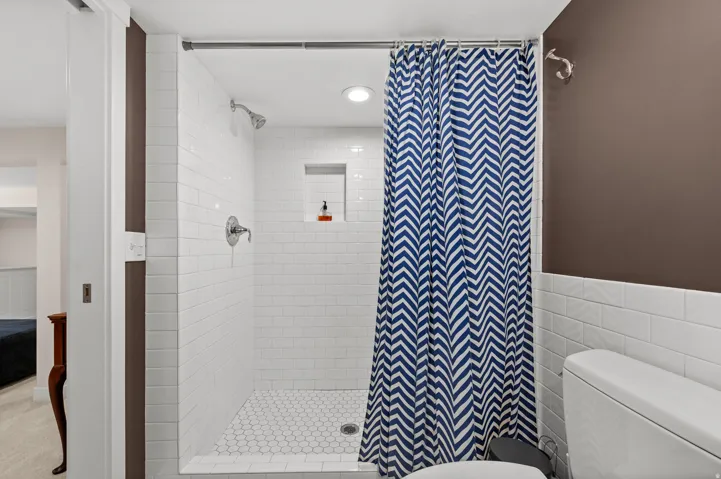 Subway tile shower surround with a built-in niche, chrome fixtures, and a hex tile shower floor