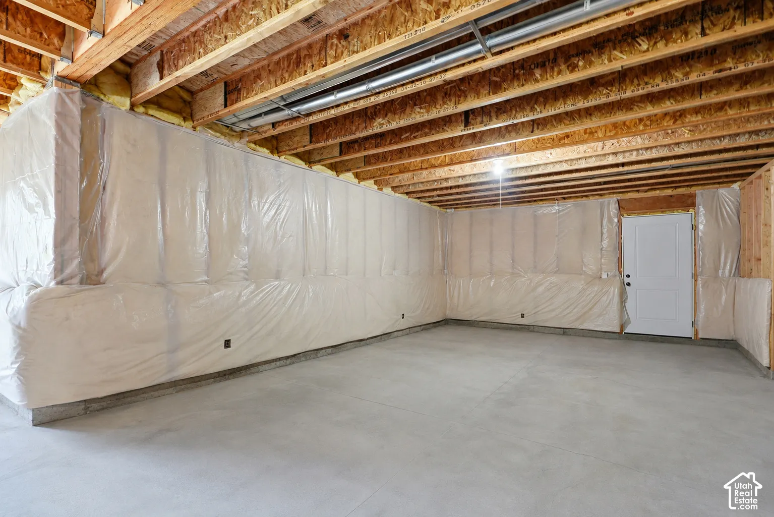 Unfinished basement with exposed wood joists, concrete flooring, and insulated perimeter walls
