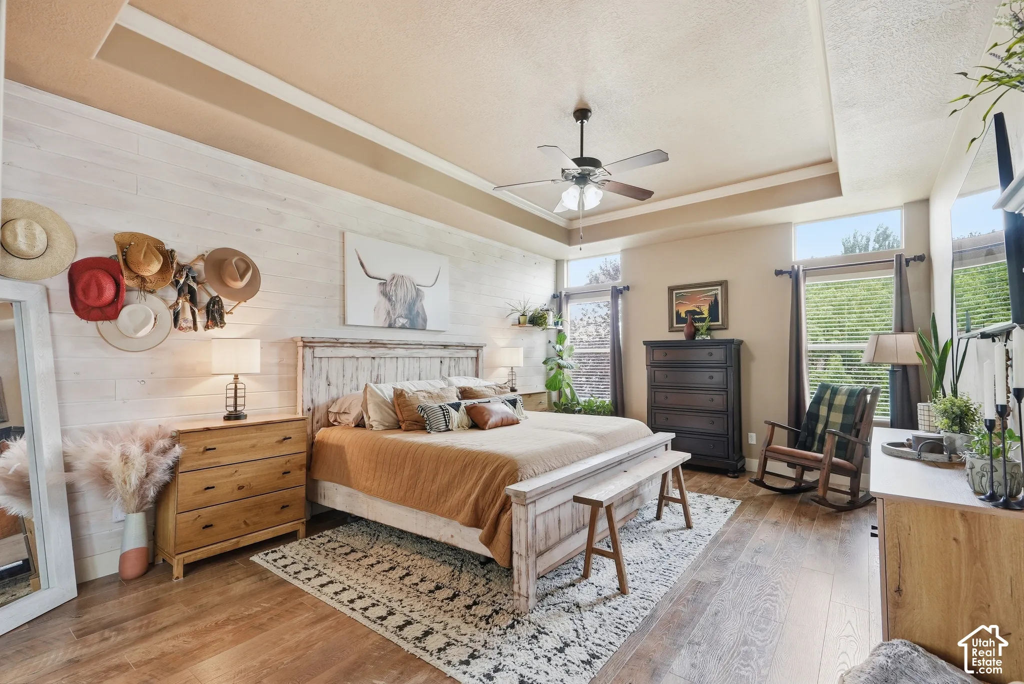 Tray ceiling with a ceiling fan, wood-finish flooring, white shiplap accent wall, and multiple windows