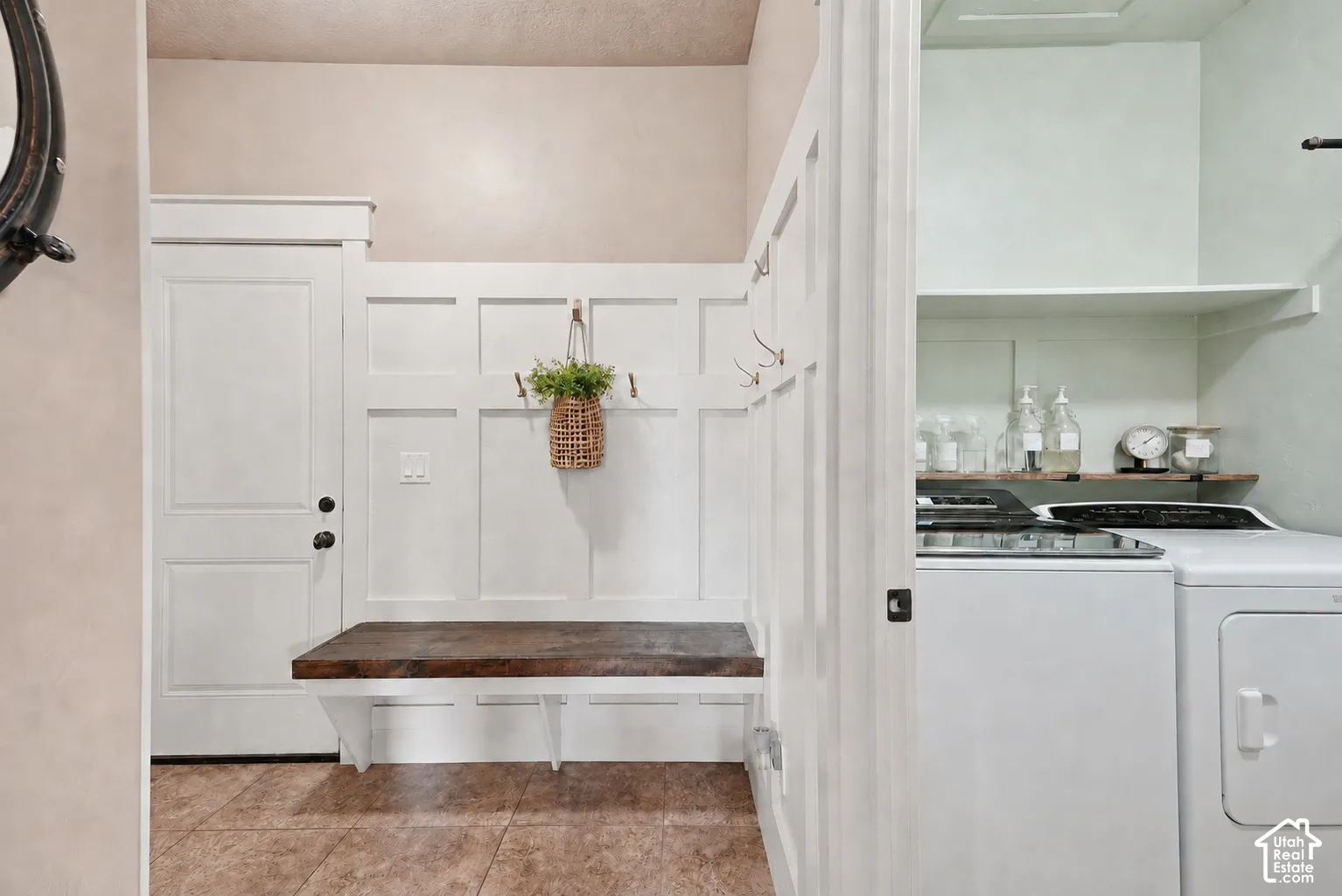 Mudroom with a built-in bench, paneling with coat hooks, and durable tile flooring