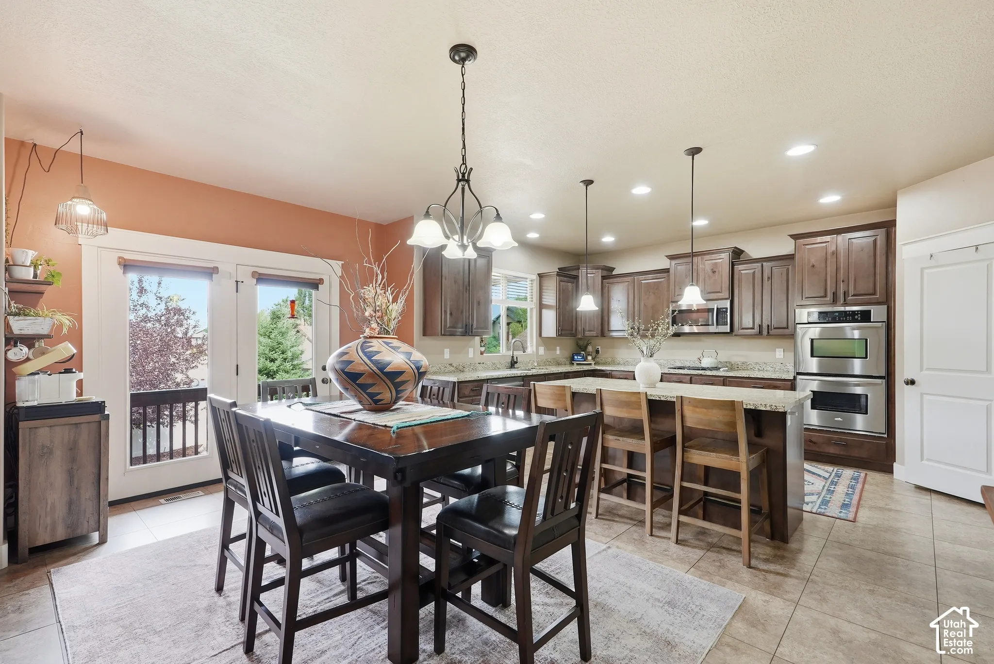 Spacious kitchen with wood cabinetry, stainless steel double ovens, a large island with bar seating, and granite countertops