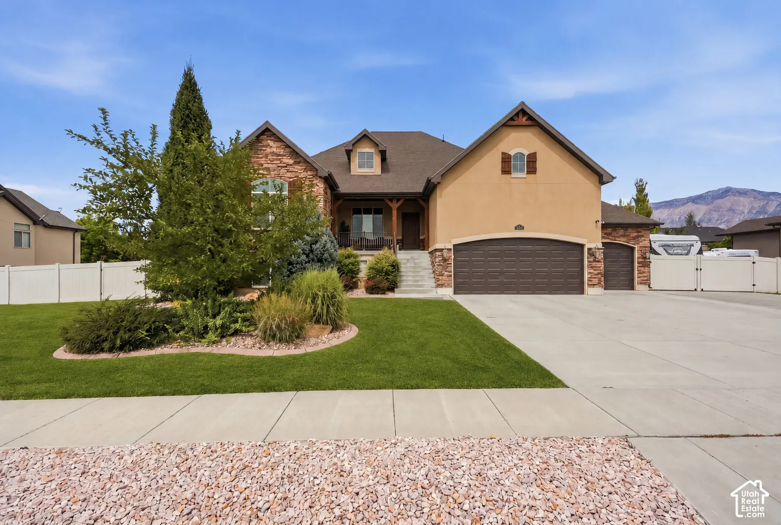 Stucco and stone exterior with a two-car garage, an additional single-car garage, and a covered porch entry