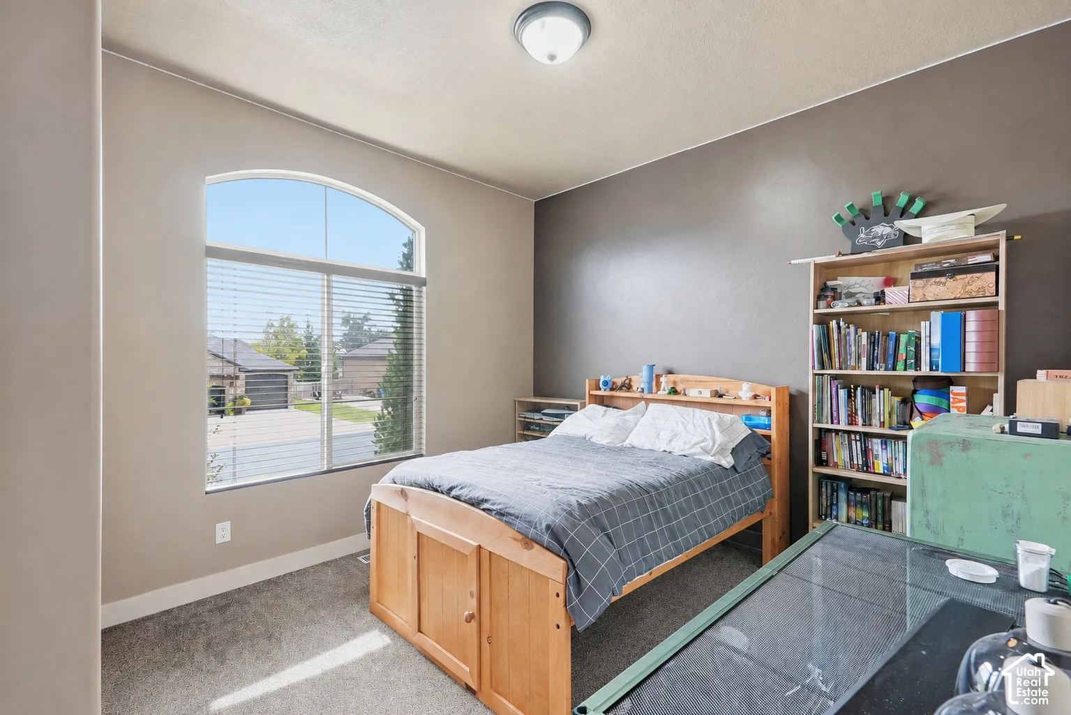 Arched window with blinds, carpeted flooring, built-in shelving, and a flush mount ceiling light