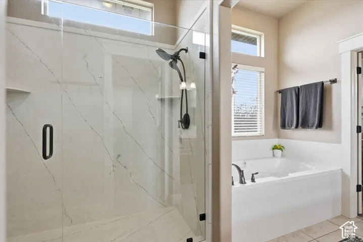 Glass-enclosed shower with a black-finished shower system, integrated shelf, and marbled-patterned wall panels