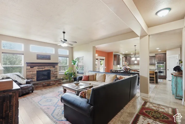 Living area featuring wood-finish flooring, a stone-clad fireplace with a wood mantel, and multiple windows