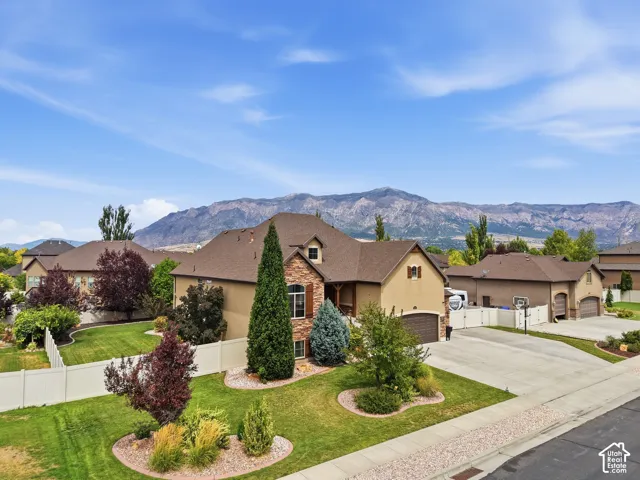 Exterior showcasing a stone and stucco facade, a multi-car driveway, and a fenced backyard with landscaped greenery