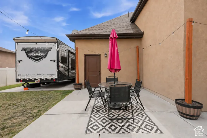 Concrete patio with stucco exterior, exterior access door, and string lighting
