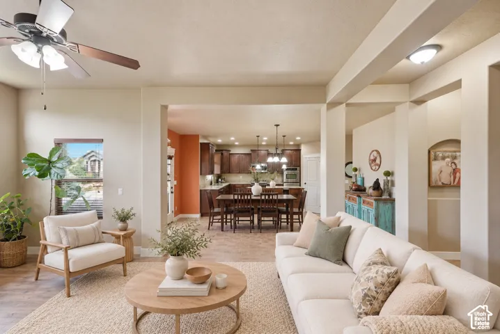 Open-concept interior featuring wood-finish flooring, recessed lighting, ceiling fan with integrated light fixture, and dark-toned cabinetry in the kitchen area