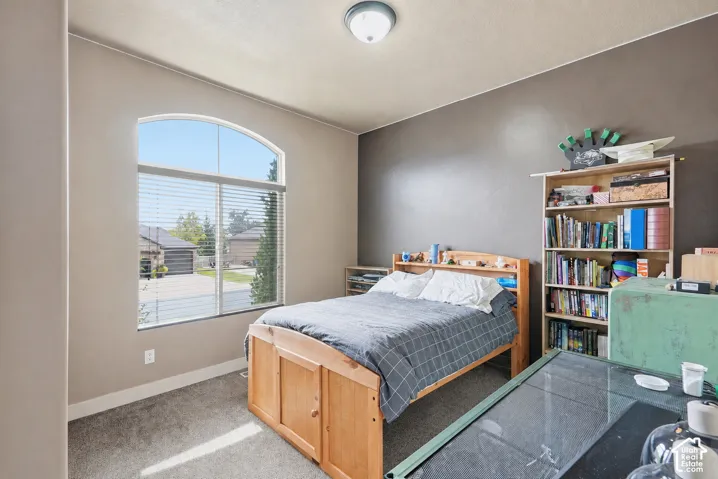 Arched window with blinds, carpeted flooring, built-in shelving, and a flush mount ceiling light