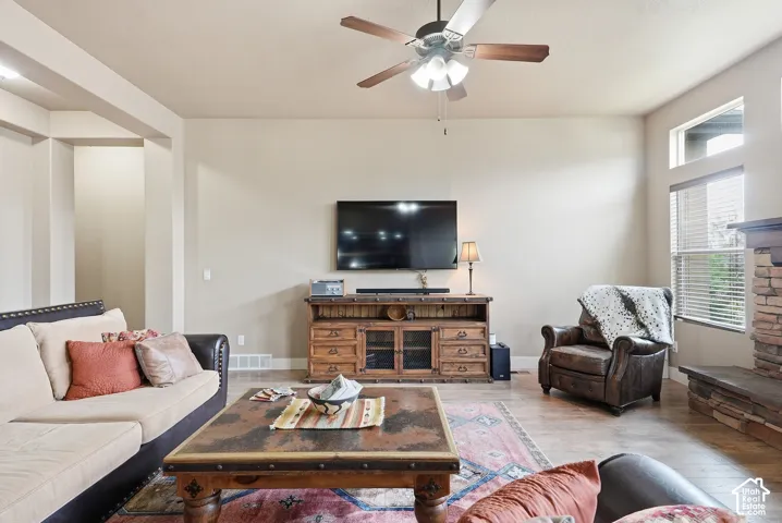 Wood-finish flooring, ceiling fan, transom windows, and built-in stone fireplace