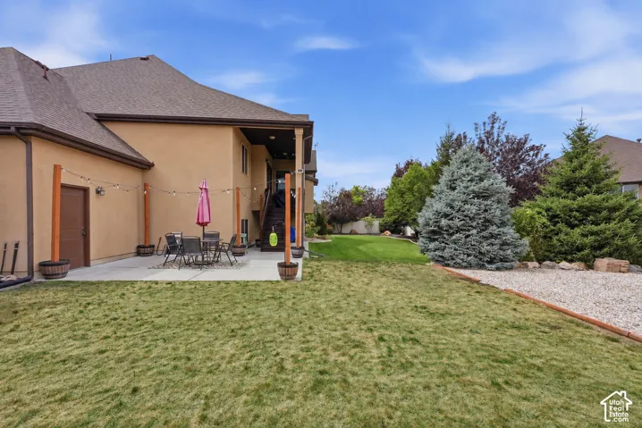 Expansive backyard featuring a concrete patio, a manicured lawn, and mature trees